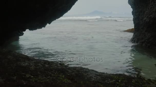 Ondas oceânicas no fundo sobre uma bela costa rochosa. Pedras olham para fora da água . — Vídeo de Stock