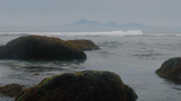 Κύματα του ωκεανού στο φόντο πάνω από μια όμορφη, βραχώδη ακτή. Πέτρες φαίνονται έξω από το νερό. — Αρχείο Βίντεο