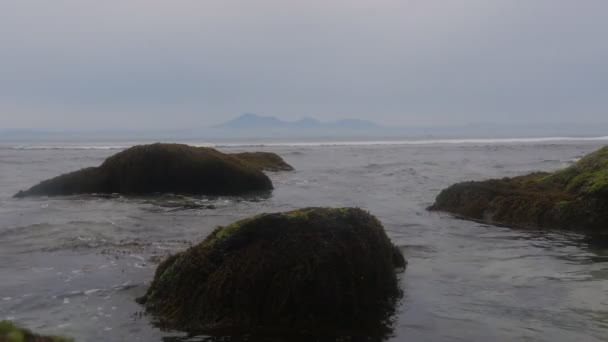 Ondas oceânicas no fundo sobre uma bela costa rochosa. Pedras olham para fora da água . — Vídeo de Stock