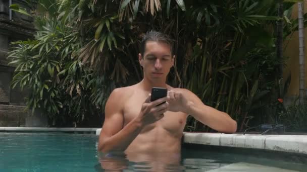 Giovane in piscina chatta su smartphone durante le vacanze estive — Video Stock