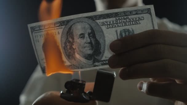 Крупным планом человек сжигает стодолларовую купюру. Бизнесмен уничтожает деньги в замедленной съемке — стоковое видео