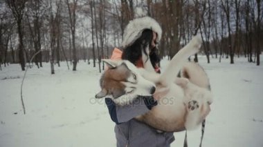 Genç kadın hussel köpek karlı bir kış parkta kollarında tutuyor. Güzel kız bir köpekle oynamayı