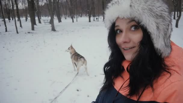 Bela jovem mulher brincando com um cão em um inverno nevado parque — Vídeo de Stock