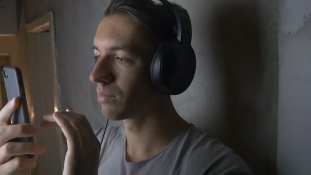 Jeune homme avec écouteurs écoutant de la musique avec smartphone — Video