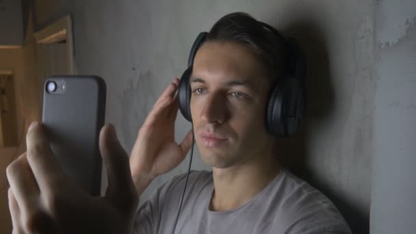 スマート フォンで音楽を聴くヘッドフォンで若い男 — ストック動画