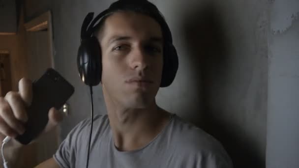 Молодий чоловік з навушниками слухає музику зі смартфоном і танцює — стокове відео