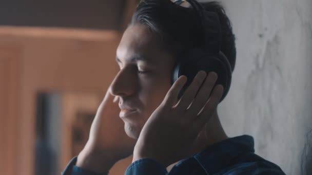 Gros plan de Jeune homme avec écouteurs écoutant de la musique — Video