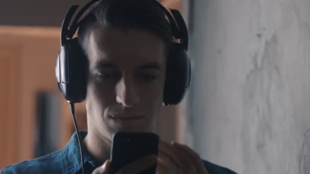 Jeune homme avec écouteurs écoutant de la musique avec smartphone — Video