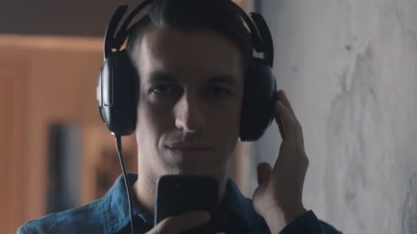 Young man with headphones listening music with smartphone — Stock Video