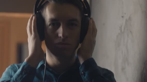 Молодой человек с наушниками слушает музыку со смартфона — стоковое видео