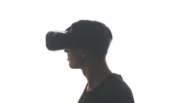 Silhouette d'un jeune homme en casque d'obtenir de l'expérience dans l'utilisation VR-casque, isolé sur fond blanc — Video