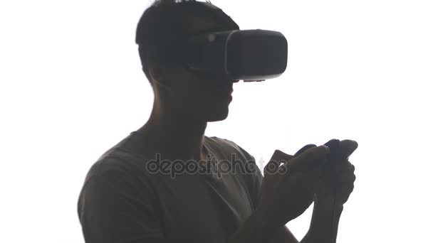 Silueta mladého muže hrát hru v vr brýle. Guy dostane zkušenosti s používáním helmu virtuální realita izolovaných na bílém pozadí — Stock video