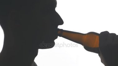 Beyaz arka plan üzerinde izole bir şişe bira içme bir genç adam silüeti kapatın