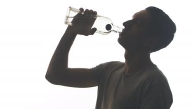 Boğaz beyaz arka plan üzerinde izole bir şişe votka içme bir sarhoş adam silüeti