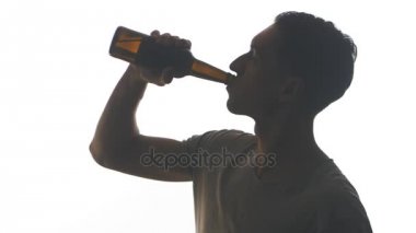 Beyaz arka plan üzerinde izole bir şişe bira içme bir genç adam silüeti