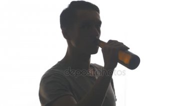 Beyaz arka plan üzerinde izole bir şişe bira içme bir genç adam silüeti