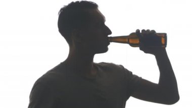 Beyaz arka plan üzerinde izole bir şişe bira içme bir genç adam silüeti