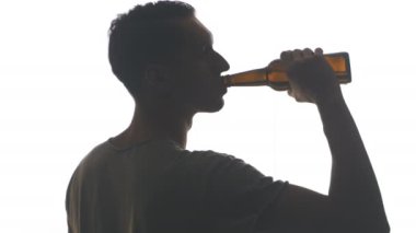 Beyaz arka plan üzerinde izole bir şişe bira içme bir genç adam silüeti
