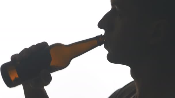 Nahaufnahme Silhouette eines jungen Mannes, der Bier aus einer Flasche trinkt, isoliert auf weißem Hintergrund