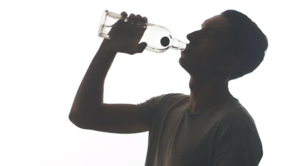 Silhouette eines betrunkenen Mannes, der Wodka aus der Kehle einer Flasche trinkt, isoliert auf weißem Hintergrund