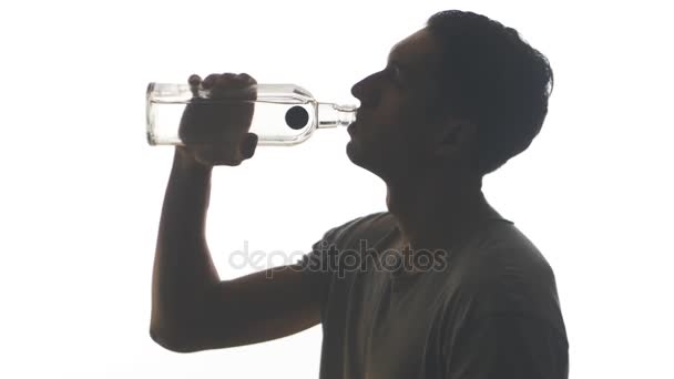 Silueta opilý muž pití vodky z láhve izolovaných na bílém pozadí — Stock video