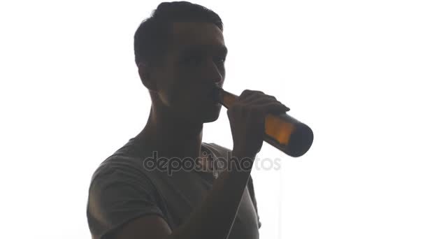 Silhouette eines jungen Mannes, der Bier aus einer Flasche trinkt, isoliert auf weißem Hintergrund — Stockvideo