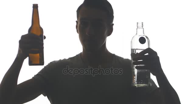 Silhouette eines Mannes, der Wodka und Bier aus einer Flasche trinkt, isoliert auf weißem Hintergrund. Konzept des Alkoholismus.