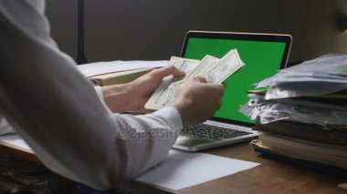 Birçok Amerikan 100 faturaları sayma işyerinde iş adamı. Maaş ya da yapım para kavramı. Masanın üzerinde yeşil bir ekran ile dizüstü bilgisayar