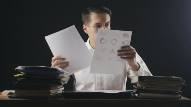 Менеджер работает с бумагами в поздний час. Молодой бизнесмен, работающий с документами на рабочем месте, временные рамки — стоковое видео