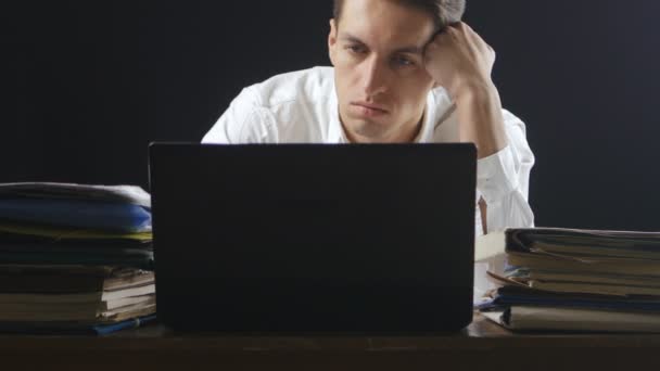 Bored businessman sitting by desk in office at night — Stock Video