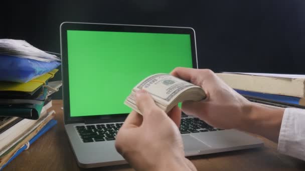Zakenman aan het werk tellen veel Amerikaanse 100 rekeningen met laptop met een groen scherm op het Bureau. Concept van salaris of maken geld. — Stockvideo