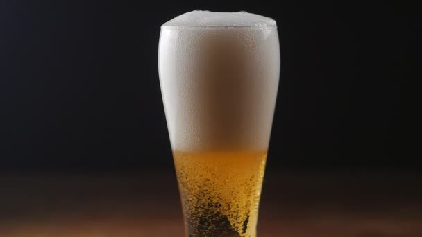 Cerveja está derramando em vidro sobre fundo preto. câmara lenta — Vídeo de Stock