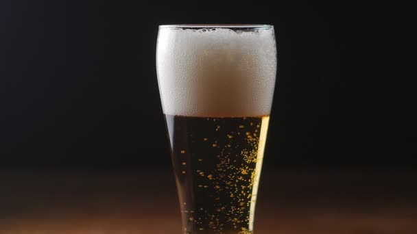 Bière froide légère dans un verre avec fond noir, ralenti 