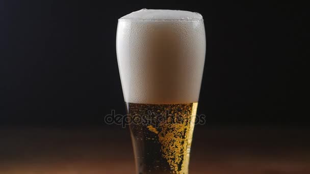 Beer is pouring into glass on black background. — Stock Video