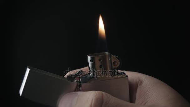 Close-up da abertura e da queima de ferro isqueiro Zippo sobre um fundo preto — Vídeo de Stock