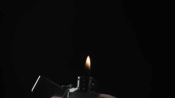 Primer plano de la abertura y la quema de hierro Zippo encendedor sobre un fondo negro — Vídeo de stock