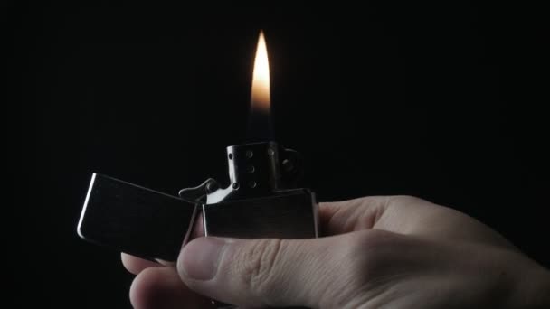Close-up van de opening en de verbranding van ijzer Zippo aansteker op een zwarte achtergrond — Stockvideo