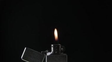 Siyah arka plan üzerine alev ile açık metal çakmak zippo