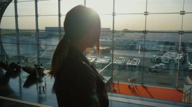 Genç kadın benim uçuş için bekliyor. Siluet büyük bir pencere arka planı