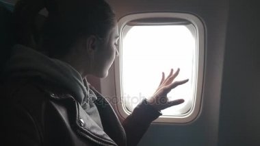 Genç kadın uçakla seyahat ve cam kenarında oturur ve görünüme sahiptir