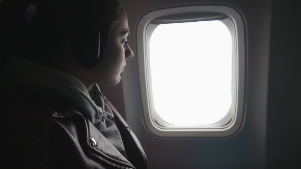 Genç kadın uçakla seyahat ve cam kenarında oturur ve görünüme sahiptir — Stok video