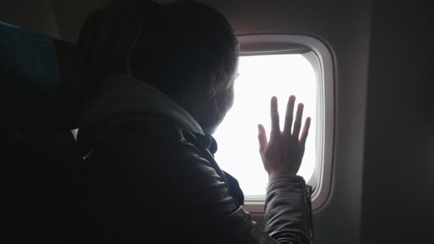 Jonge vrouw met het vliegtuig reist en zit bij het raam en geniet van het uitzicht — Stockvideo