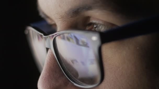 Gros plan de Réflexion sur les lunettes et les yeux des jeunes hommes naviguant sur les sites Internet — Video