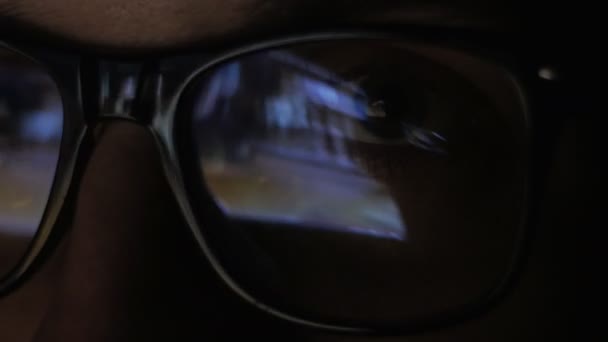 Reflejo de cerca en las gafas de un hombre viendo una película por la noche. Doble exposición del tipo que ve el video. Macro — Vídeos de Stock