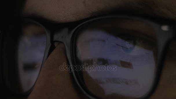 Close up of Reflection at glasses and eyes of young man surfing web sites on the Internet — Stock Video