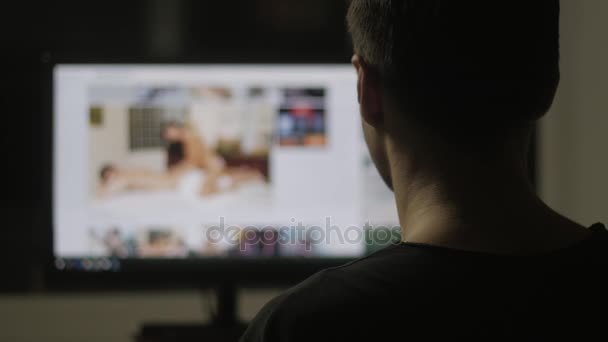 Young man watching surfing pornography site on the web at night at home — Stock Video