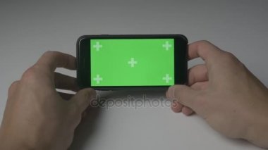 Yakın kadar adam tutarak Smartphone dokunmatik ile yeşil ekran Chroma Key yatay pozisyonda