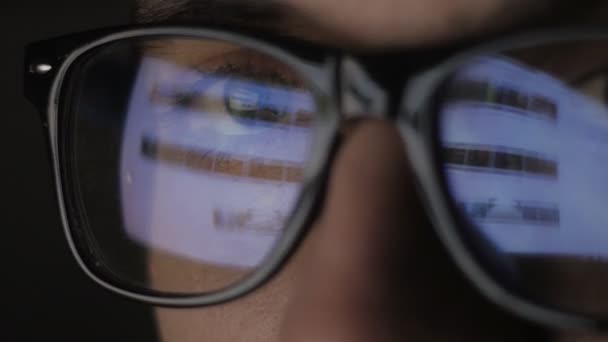 Close up of Reflection at glasses and eyes of young man surfing web sites on the Internet — Stock Video