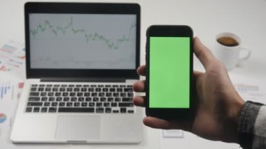 Smartphone ile yeşil ekran chroma anahtar beyaz ofis masa artalanını adlı tutan işadamı.