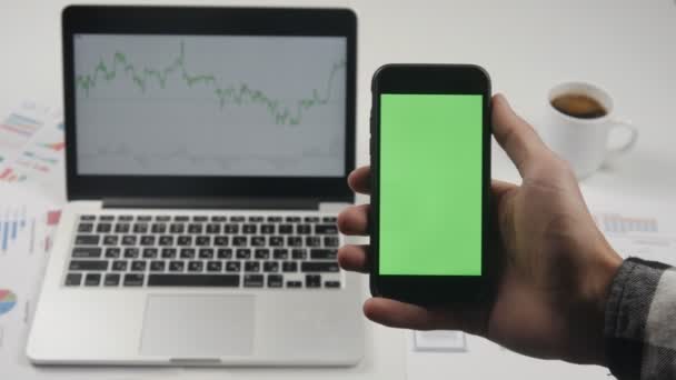 Επιχειρηματίας κρατώντας smartphone με πράσινη οθόνη chroma κλειδί στο φόντο λευκό γραφείο τραπέζι. — Αρχείο Βίντεο